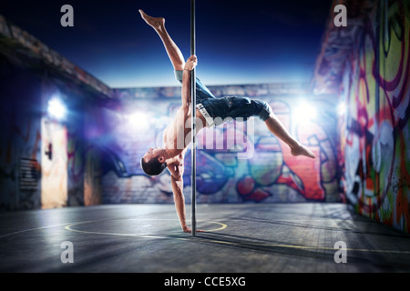 Junge starke Pole Dance-Mann auf städtischen Hintergrund. Stockfoto