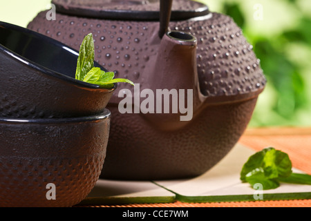 Frische Teeblätter und Wasserkocher im Garten Stockfoto