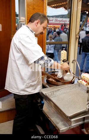 Verkäufer arbeiten bei Braten mit Mandeln an deutschen mobilen Verkaufsstand am Messe, Deutschland, Europa Stockfoto