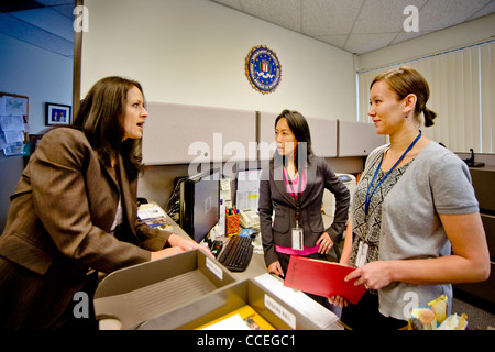 Drei weibliche FBI-Agenten diskutieren einen Fall in Santa Ana, CA, Büro. Beachten Sie Filipino-Amerikaner im Zentrum und FBI Logo auf Wand. VERÖFFENTLICHT Stockfoto