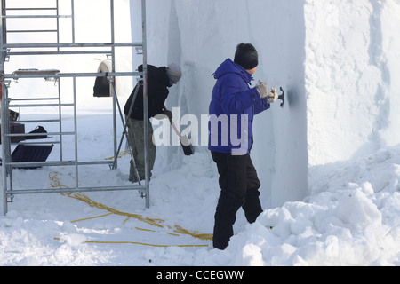 Zwei Schnee Bildhauer Meißeln Außenwände von Ice Hotel in Kanada Stockfoto