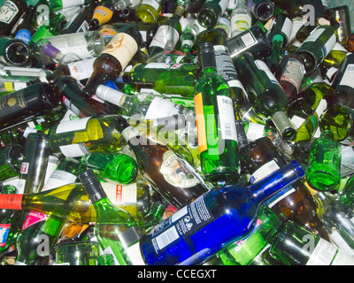 Viele verschiedene farbige/farbigen Glas Wein und Bier Flaschen gehäuft zusammen in ein recycling Altglascontainer. Stockfoto