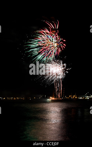 Rote und grüne Feuerwerk am Fluss mit Spiegelbild im Wasser Stockfoto