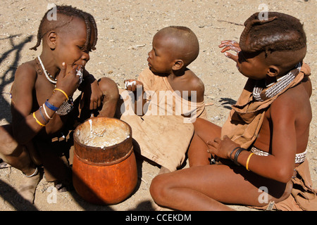 Himba-Kinder essen Maisbrei im Dorf in der Nähe von Opuwo, Namibia Stockfoto