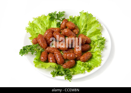 gegrillte Würstchen auf grünem Salat mit isoliert auf weiss Stockfoto