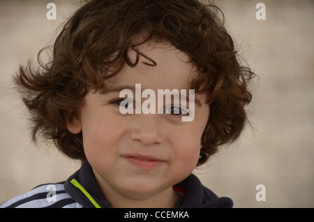 Ein hübscher Junge mit langen Haaren lächelt in die Kamera. Stockfoto