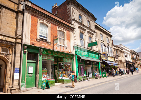 Geschäfte und Cafés und Menschen beim Einkaufen in High Street, Glastonbury, Somerset, England. Stockfoto