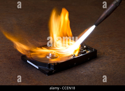 symbolische Technologie Thema zeigt eine Fackel Schweißspitze und schneidigen Flamme brennt eine feste Festplatte Stockfoto