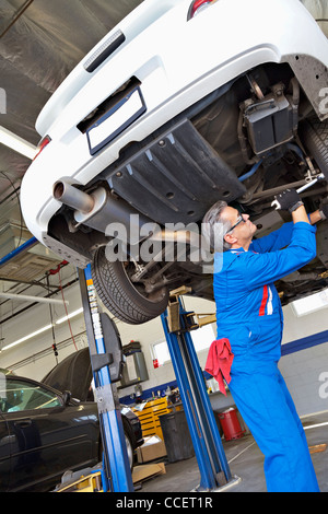 Niedrigen Winkel Ansicht des leitenden Mechaniker arbeiten unter Auto Stockfoto