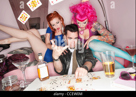 Mann, schaukelnden Spielkarten in Luft mit Frauen, die neben ihm sitzen Stockfoto