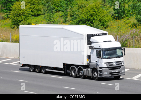 Seite und der Vorderseite der Weißen unmarkierte Saubere LKW-Lieferung Lkw Lkw und artikuliert aerodynamische Form Anhänger entlang der Autobahn M25 Essex England Großbritannien fahren Stockfoto