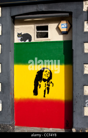 Schablone Kunstwerk von Bob Marley auf rote, gelbe und grüne Flagge mit der Malerei der Katze über Cardiff South Wales UK Stockfoto