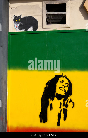 Schablone Kunstwerk von Bob Marley auf rote, gelbe und grüne Flagge mit der Malerei der Katze über Cardiff South Wales UK Stockfoto