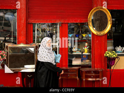 Eine griechische muslimische Dame vorbei an einem alten Antiquitätengeschäft in der Stadt Komotini Rodopi Präfektur, Thrakien, Griechenland. Stockfoto