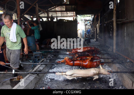 31. Dezember 2010 - Cotabato, Philippinen - Filipino Arbeiter in einer Fleischerei in den südlichen Philippinen Cotabato vorzubereiten und gebratene Schweine, ein beliebtes Gericht für Feiertage und besondere Anlässe. Die Schweine werden auf Spieße über Kohlen geröstet. (Kredit-Bild: © Jeoffrey Maitem/ZUMApress.com) Stockfoto