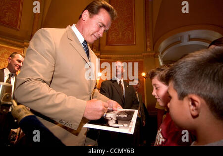 11. Juli 2004; Sacramento, Kalifornien, USA; Kaliforniens Gouverneur ARNOLD SCHWARZENEGGER unterzeichnet ein altes Foto von sich selbst aus seinem Bodybuilding Tage für Austin Palmi, 8, zentrieren und Mauricio Salazar, 5 von Sacramento, nachdem er der California-Haushalt in der State Capitol Montag, 11. Juli 2005 unterzeichnet. Stockfoto