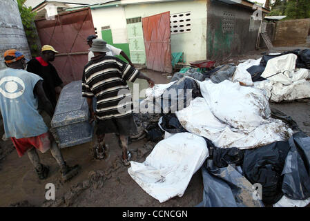 GONAIVES, HAITI; 21.09.04: Verwandten Retieve den Körper eines Familienmitgliedes aus einem Haufen von Leichen in Leichensäcken außerhalb der Leichenhalle des La Providence Hospital in Gonaives Dienstagabend.  Mehr als 100 stellen warteten, begraben zu werden, laut Erich Baumann des internationalen Roten Kreuzes.  Er sagte, die Stockfoto