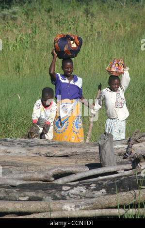 18. März 2004, Bala, Malawi - geht eine junge Mutter mit ihren beiden Kindern auf einem lokalen Markt tragen Körbe gekochten Reis auf ihren Köpfen in der traditionellen afrikanischen Stil.  (Credit: David Snyder/ZUMA Press) Stockfoto