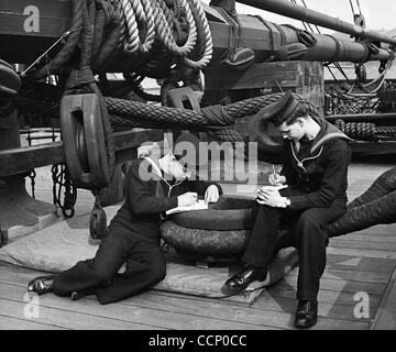 NelsonÕs altes Schiff wurde in den Dienst als Schulschiff gedrückt. Hier schreiben zwei britische Seeleute ihre Briefe nach Hause auf dem Holzdeck, umgeben von den Blöcken und Seile von anno dazumal. Stockfoto