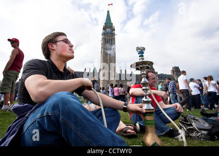 20. April 2010: mit der Peace Tower im Hintergrund, ein junger Mann raucht einige Cannabis während der 420 Rallye am Parliament Hill in Ottawa, Ontario, Kanada. 420, 04:20 oder 4/20 (ausgeprägte vier-zwanzig) bezieht sich auf den Konsum von Cannabis und durch Verlängerung, eine Möglichkeit, sich mit Cannabis Droge Sub identifizieren Stockfoto