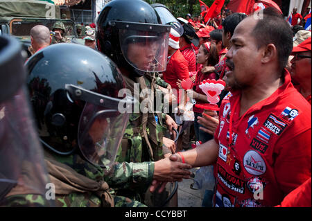 27. März 2010 neu - Bangkok, Thailand - Thai Soldat in anti-Kampfausrüstung Händeschütteln mit Anti-Regierungs-Demonstranten beim verlassen das Gelände des buddhistischen Tempels in Nähe der Regierungsgebäude, während Anti-Regierungs-Demonstranten waren jubeln und schreien Sieg als Soldaten in ihren barr Stockfoto