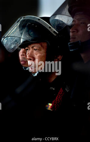 5. April 2010 - Bangkok, Thailand - Thai Riot Police Officer zusieht wie Anti-Regierungs-Demonstranten das Gebäude Büros der Wahlkommission in der Regierung Komplex auf Chaeng Wattana Road in Bangkok, Thailand brach in. Rothemden fordern die Wahlkommission die Lon geben Stockfoto