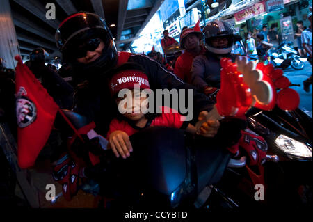 6. April 2010 - trägt Bangkok, Thailand - ein kleines Mädchen der Anti-Regierungs-Kopfband und halten ein riesiges Paar Kunststoff Klappern während der massiven Kundgebung der Rothemden in Rajaprasong. Die thailändische Armee wurde auf den Straßen von Bangkok zu helfen, Bereitschaftspolizei angesichts der Rothemden eingesetzt. Hunderte von Stockfoto