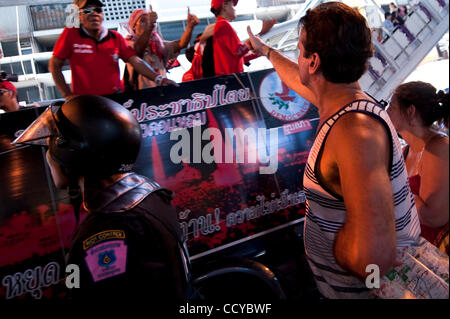 6. April 2010 - Bangkok, Thailand - A Tourist hält einen Stadtplan und einen Daumen bis zu den red Shirt Demonstranten zeigt, wie sie entlang der wohlhabenden Viertel von Bangkok am 6. April 2010 Parade. Die Demonstrationen vierte Woche der anti-Regierungs-Demonstranten stürmen die Straßen von Bangkok, Eingabe der Stockfoto