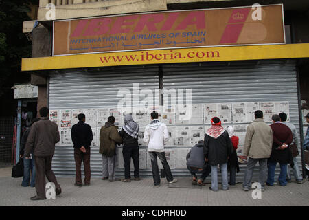 7. Februar 2011; Kairo, Ägypten. Eine Gruppe von Männern lesen die Zeitungen, die auf der Fassade eines Reisebüros in Tahrir-Platz angezeigt werden. Wie das Leben wieder normal in Kairo geht, sind Demonstranten auf dem Tahrir-Platz nach einer gut organisierten Alltag leben. Stockfoto