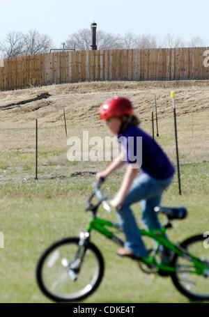 17. März 2011 - Weatherford, Texas, USA - 17.03.2011.  Das Fackel-Rohr installiert von Aruba Erdöl auch Erdgas erhebt sich über RILLEY RUGGERIO, als sie ihr Fahrrad auf der hinteren Veranda der Familien in der Nähe von Decatur, Texas nach Hause reitet. Luftqualitätsstandards dass wurde festgestellt ich Bundesstandards unterschreiten Stockfoto