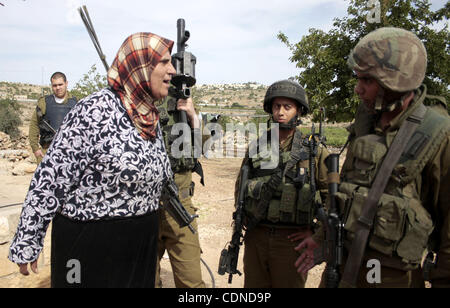 25. Mai 2011 - Hebron, Westjordanland, Palästina - israelische Soldaten Wache stehen Landwirtschaft Land teilweise zu zerstören und eine Palästinenserin widersprechen die israelischen Soldaten in der Nähe der West Bank von Hebron auf der anderen Straßenseite von der israelischen Siedlung von Kiryat Arba am 25. Mai 2011. als ein respon Stockfoto
