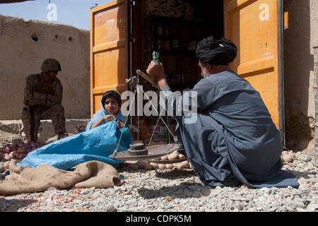 27. April 2011 - Stadt des Naw Zad, Naw Zad District, Helmand, Afghanistan - ein lokalen Anbieter wiegt Kartoffeln auf einer provisorischen Skala mit Hilfe seiner Tochter als eine eine Marine von Lima Company, 3. Bataillon des 2. Marineregiment bleibt im Hintergrund während einer gemeinsamen Patrouille mit ANA-Soldaten in den Bazar Stockfoto