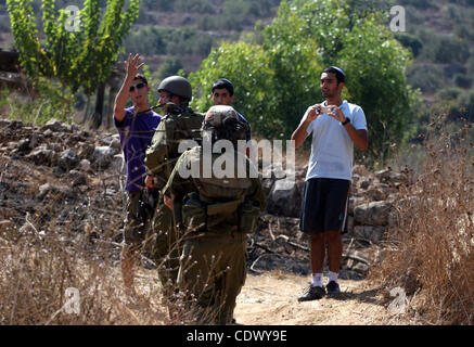 Israelische Soldaten bewachen bewaffnete jüdische Siedler aus der Grossheirath-Siedlung in der Nähe von Mitglieder der pro-palästinensische Freiwilligen-basierte Kampagne, zu intervenieren und reagieren auf Fälle von Gewalt gegen Palästinenser jüdische Siedler im Westjordanland, im Westjordanland-Dorf von Nabi Saleh, in der Nähe von Ramalla Stockfoto