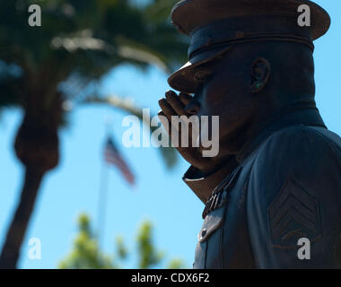 Eine amerikanische Flagge fliegt in der Ferne über eine Bronzestatue, auch bekannt als der Marine-Denkmal, eine begrüssende uns Marine Corps Unteroffizier im Semper Fi Park im Bereich Pier Schüssel von San Clemente am 31. Juli 2011. San Clemente Semper Fi Park und Marine-Denkmal, mit US Marine Corps Base Camp Pendleto Stockfoto