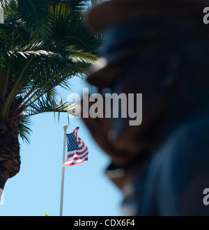 Eine amerikanische Flagge fliegt in der Ferne über eine Bronzestatue, auch bekannt als der Marine-Denkmal, eine begrüssende uns Marine Corps Unteroffizier im Semper Fi Park im Bereich Pier Schüssel von San Clemente am 31. Juli 2011. San Clemente Semper Fi Park und Marine-Denkmal, mit US Marine Corps Base Camp Pendleto Stockfoto