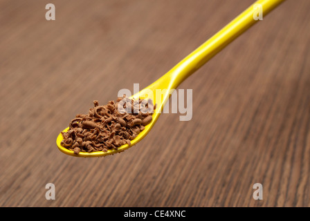 Teelöffel voll mit Schokolade Späne auf einer hölzernen Hintergrund-Nahaufnahme Stockfoto