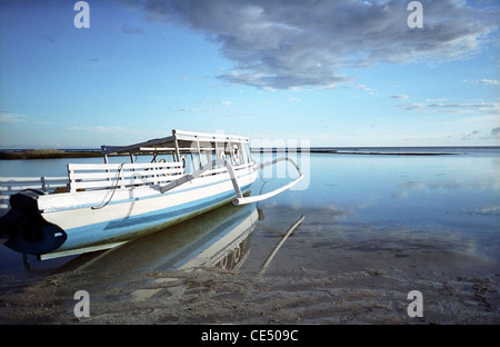 Ein Tourist Auslegerboot sitzt auf dem Sand in einer Lagune in der Abenddämmerung auf der Insel Gili Air in Indonesien Stockfoto