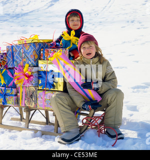 Junge und Mädchen mit Schlitten beladen mit Geschenken, Schnee, Elsass, Frankreich, Europa Stockfoto