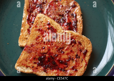 Offenes Gesicht Erdnussbutter und Marmelade Vollkorn Toast auf einem Teller grün Stockfoto