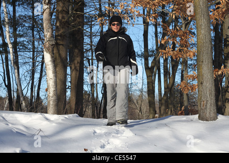 Wandern in der Wildnis im Schnee mit Bäumen hinter Frau Stockfoto