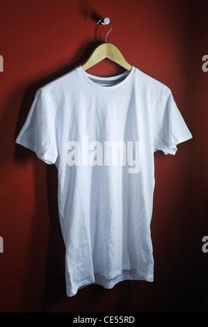 Ein weißes t-Shirt auf einen hölzernen Kleiderbügel, leuchtend roten Hintergrund Stockfoto