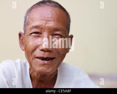 Porträt von senior asiatischen glücklich mit Zahnproblemen Lachen und Blick in die Kamera gegen gelbe Wand Stockfoto