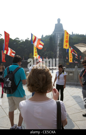 weibliche kaukasische Touristen fotografieren am Di Tan vor dem Tian tan großen Buddha im Dunst der Smog Ngong Ping Hongkong Sonderverwaltungsregion Hongkong Stockfoto