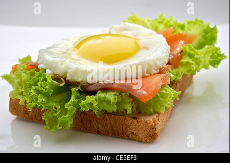 Fisch-Frühstück mit Rührei und Räucherlachs auf Toast, auf weißen Teller serviert Stockfoto