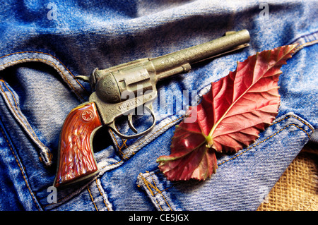 Spielzeug Pistole Pistole und blaue Jeans mit Herbst rote Blatt-Muster Stockfoto