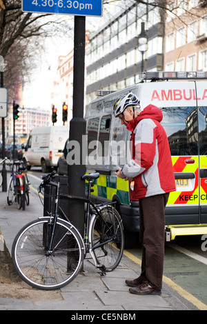 Tottenham Court Road West End London älterer Mann roten anorak Helm schützt Fahrrad pedal cycle Strassenlaterne street scene Gehsteig Bürgersteig Stockfoto