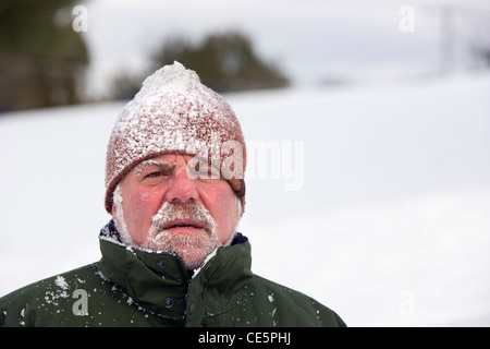 Portrait der Kaukasischen älterer Mann mit Schnee bedeckt stricken Hut und Schnurrbart im Winter Stockfoto