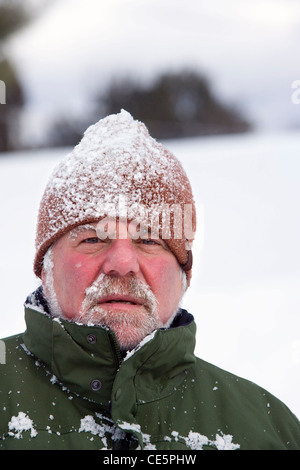 Portrait der Kaukasischen älterer Mann mit Schnee bedeckt stricken Hut und Schnurrbart im Winter Stockfoto