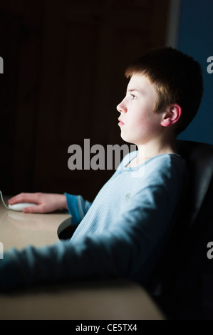 Ein 12 Jahre alter Junge auf seinem Computer auf Facebook Internet Website mit sehr geringen Schärfentiefe Stockfoto