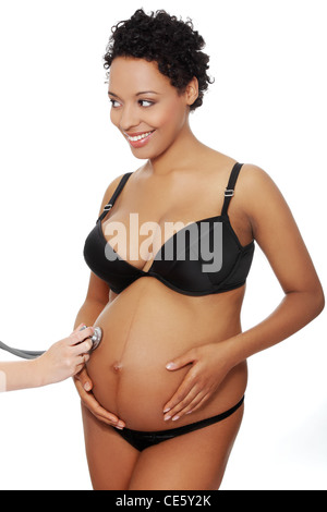 Vordere vierw Porträt einer jungen schönen Frau in ihrem Bauch mit einem Stethoskop, auf weißem Hintergrund isoliert untersucht. Stockfoto